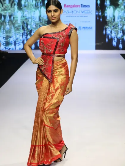 A full-length runway shot of the red Kanchi saree paired with the modern embroidered crop blouse, demonstrating a perfect blend of traditional and contemporary styles.