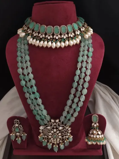 A lovely pastel green Victorian jewellery set. It includes a choker with pearl drops, a matching long necklace, and earrings, perfect for a subtle yet regal look.