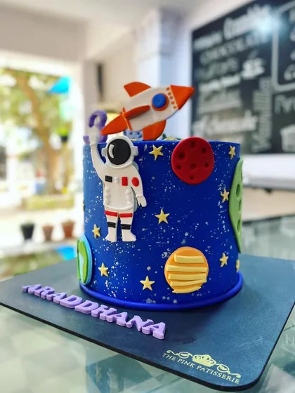 An out-of-this-world space-themed cake. The deep blue design features an astronaut, a rocket, and planets, perfect for a future space explorer's birthday.