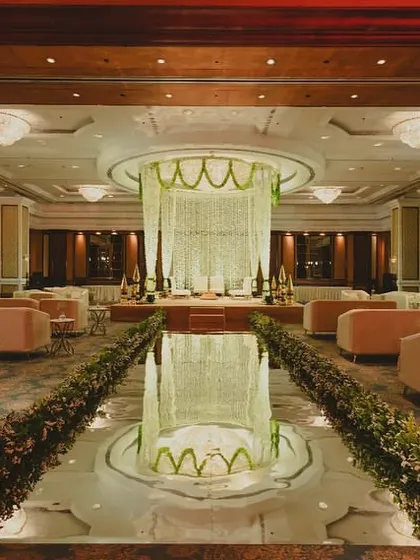 For a grand ballroom reception, we designed a sophisticated and elegant experience. The layout features a central water body reflecting a magnificent floral chandelier, surrounded by plush lounge seating, transforming the entire space into a luxurious indoor garden.