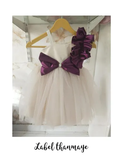 A simple yet elegant party frock with a large purple bow and shoulder detail.
