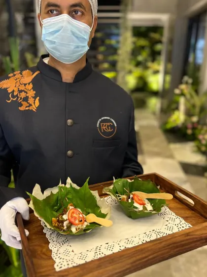 A server holds a tray with appetizers served in natural leaf bowls. This eco-friendly and stylish presentation is perfect for outdoor or rustic-themed weddings, showcasing our attention to detail.
