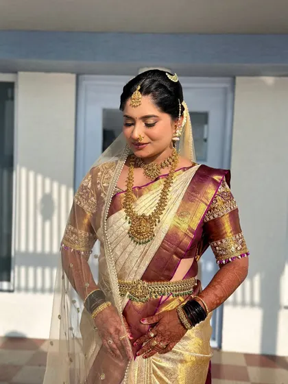 A moment of quiet elegance. This bride's makeup is subtle yet striking, with a focus on a smooth base, soft eyeshadow, and a traditional maang tikka that completes her muhurtham attire.