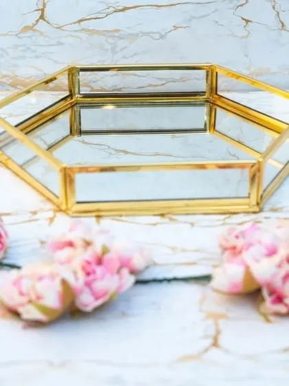 For a unique and contemporary look, we offer this hexagonal mirrored tray with a gold-finish frame. It serves as a stunning base for presenting gifts and doubles as a chic decor item for the home.