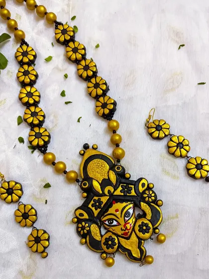 This black and gold Durga pendant is paired with a floral chain, creating a unique and artistic fusion. The matching three-flower earrings complete this elaborate festive set.