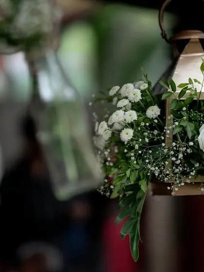 A close-up of the delicate floral decor for a Sangeet, featuring white roses and baby's breath in a hanging lantern.