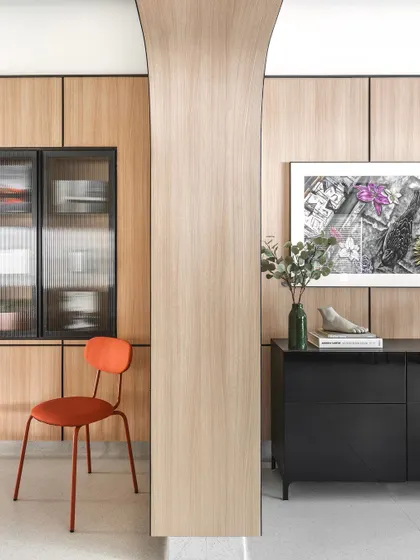 A detail shot of the reception area, showing the curved pillar clad in oak laminate. This element softens the space and adds a sculptural quality to the interior architecture.