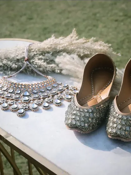 A beautiful flat-lay of the bride's accessories, including her stunning necklace and embellished juttis, capturing the details of her look.
