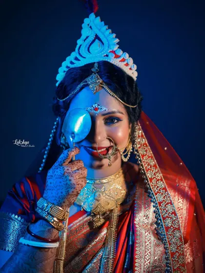 A creative and playful portrait of the Bengali bride. The use of blue lighting and a prop creates a modern, artistic twist on a traditional bridal shot.