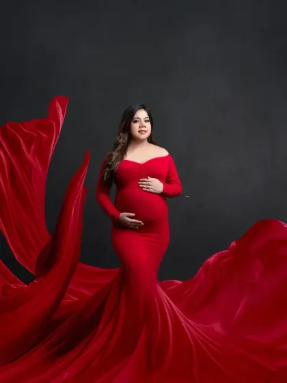 Elegance in motion. This portrait showcases a beautiful red gown with a long, flowing train, expertly arranged to create a sense of grandeur and movement.