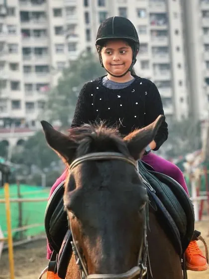 A young rider looks confident and happy during her lesson. We focus on making horse riding a fun and empowering activity for children.