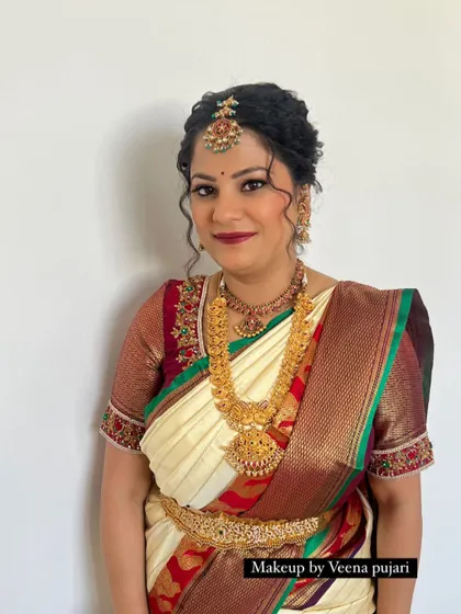 This bride opted for a classic look with a modern twist. The curly tendrils framing her face add a touch of softness to the traditional updo and silk saree.