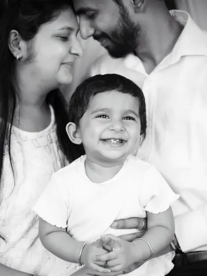 A joyful black and white family portrait, with the baby's bright smile at the center of his parents' loving gaze.