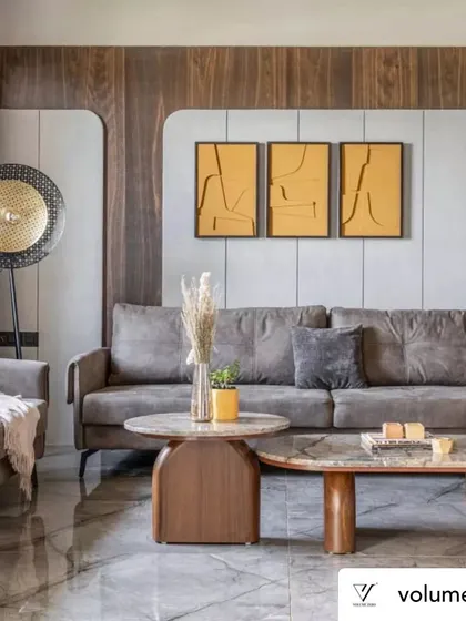 In the living room, I designed the back wall with curved wood panels framing a textured grey surface. This softens the lines of the room and creates a sophisticated backdrop for the comfortable sofa and abstract art, balancing modern design with a cozy feel.