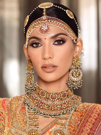 A close-up of a traditional South Indian bridal look. Notice the precision of the eyeliner and the way the makeup complements the intricate gold jewelry, techniques we practice in class.