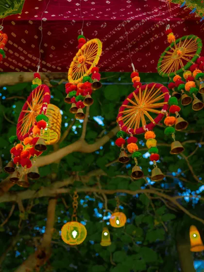 Colorful and traditional hanging decor, featuring thread-work wheels, pompoms, and bells, added a festive and folksy charm to this outdoor event.