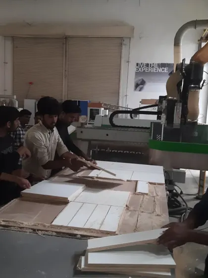 The CNC machine in action. Students carefully remove precisely cut parts from the nested layout, showcasing the efficiency of digital fabrication.