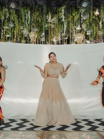The bride takes center stage with her backup dancers on a custom-floored stage, under a canopy of hanging foliage and disco balls.