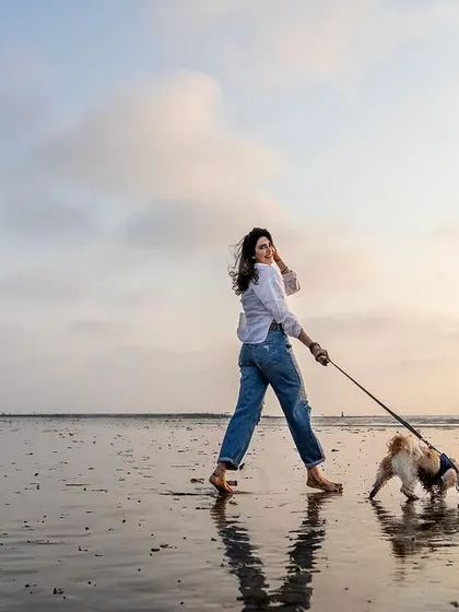 A quiet walk on the beach at sunset with your best friend. This beautiful, reflective moment between a woman and her dog shows the peaceful side of outdoor photography. The golden light and wet sand create a stunning natural backdrop.