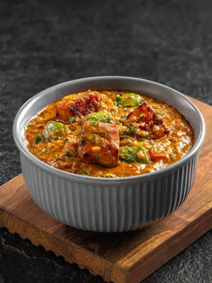 A flavorful Kadai Paneer, with chunks of paneer and bell peppers in a thick gravy. The presentation is simple and focused on the food.