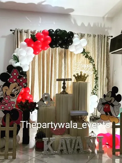 A classic Mickey and Minnie Mouse theme with a red, black, and white balloon arch.
