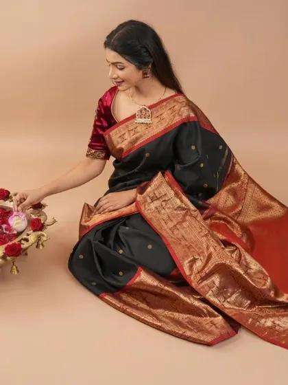 A classic black Kanjivaram with a magnificent red and gold border. This shot captures a moment of quiet elegance, perfect for traditional ceremonies.