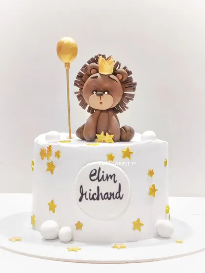 A simple and sweet first birthday cake featuring an edible lion king topper, golden stars, and a balloon. The design is clean, elegant, and adorable.