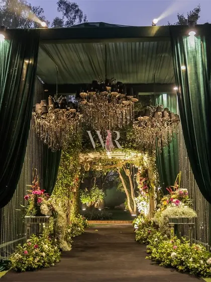 The entrance to this engagement party was designed as a grand reveal. Emerald green velvet drapes part to unveil a floral archway and sparkling chandeliers, offering guests a first taste of the enchanted garden theme that awaited them inside.
