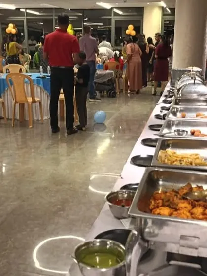 A full view of our catering setup for a birthday party, with guests enjoying the food in a decorated party hall.