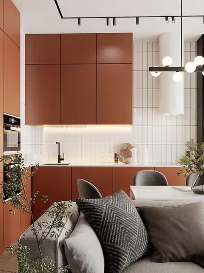 A modern kitchen and dining area in a warm, earthy color palette. The terracotta-colored cabinets and minimalist white-tiled backsplash create a cozy and contemporary open-plan living space.
