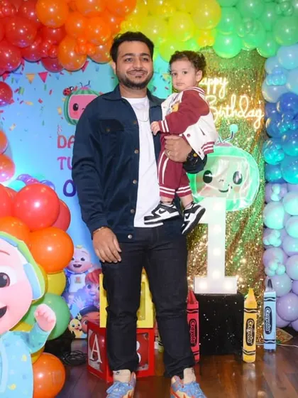 A father and son posing in front of the vibrant party backdrop.