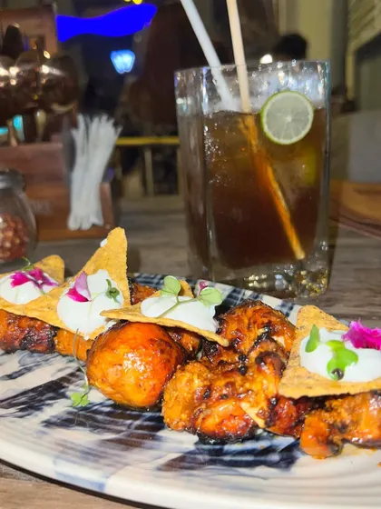 A close-up of the creatively plated chicken tikka nachos and a mocktail at Dutchman's Port, showing off their culinary fusion.