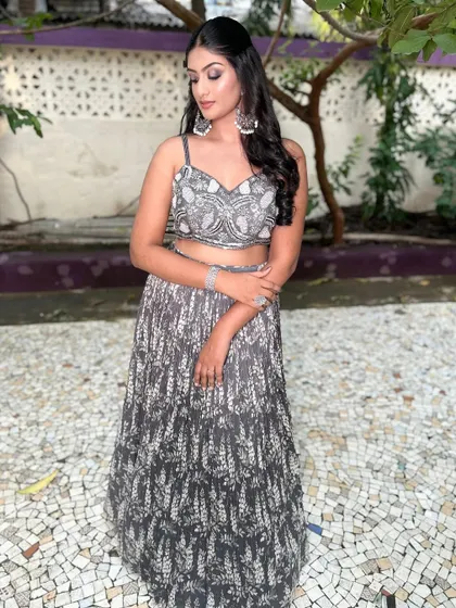 A client in a sophisticated grey and silver handwork Indo-Western lehenga. The modern print and embellished crop top create a chic and elegant look.