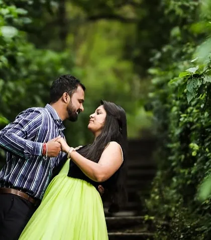 A sweet, natural moment between a couple during their pre-wedding shoot in a green, leafy location. The lime green gown adds a fresh pop of color.