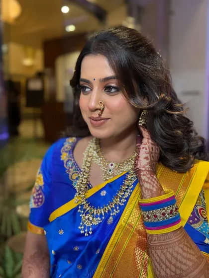 A beautiful engagement look. The bride's vibrant blue and yellow saree is paired with traditional jewelry and a soft, glamorous makeup style.