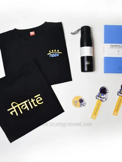 A creative and modern welcome kit featuring two custom t-shirts with Hindi and English branding, a water bottle, a notebook, and fun astronaut-themed accessories, showing our ability to match a company's unique vibe.
