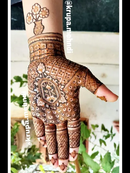 An intricate design with a central motif and a unique floral vase tattoo on the wrist. This shows how we can mix different styles to create something personal for you.