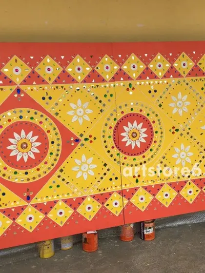 A finished panel with bright yellow and red geometric and floral patterns, typical of Lippan art. The use of mirrors in the design reflects light and adds a dynamic quality to the piece.