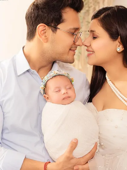 A beautiful portrait of new parents with their precious newborn. The soft white wrap and gentle hold create a feeling of peace, love, and new beginnings.