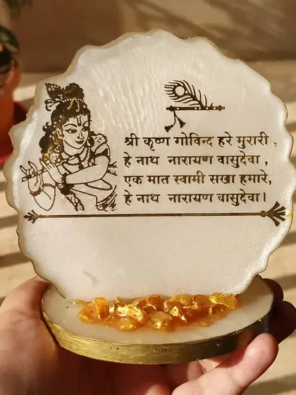 To bring positive energy to your home or workspace, I create simple and elegant mantra frames like this Shree Krishna piece. It features a beautiful prayer and an illustration of Lord Krishna, set in a pearlescent resin base with golden crystal accents.