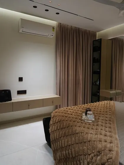 A wide view of a serene bedroom, featuring a floating console, a full-length mirror, and a glass-paneled display wardrobe.
