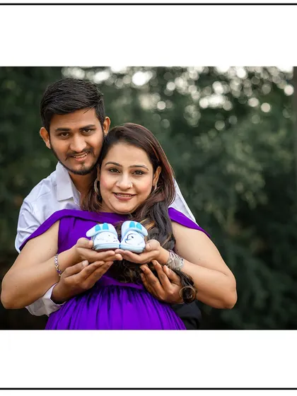 The couple proudly presenting a pair of tiny baby shoes. This is a classic prop that symbolizes the new life they are waiting for.