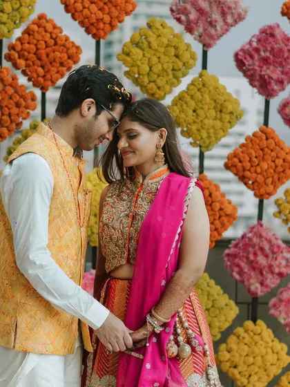 A romantic portrait of the couple at their Mehndi, framed by a vibrant wall of marigolds.