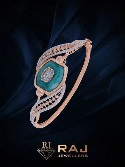 This contemporary bracelet features a central squared green stone, set on a sleek open-ended band with detailed CZ work. It is a modern and chic accessory.