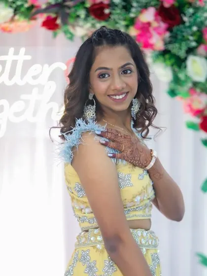 A side profile showing her soft curls and the pretty floral background of the event.