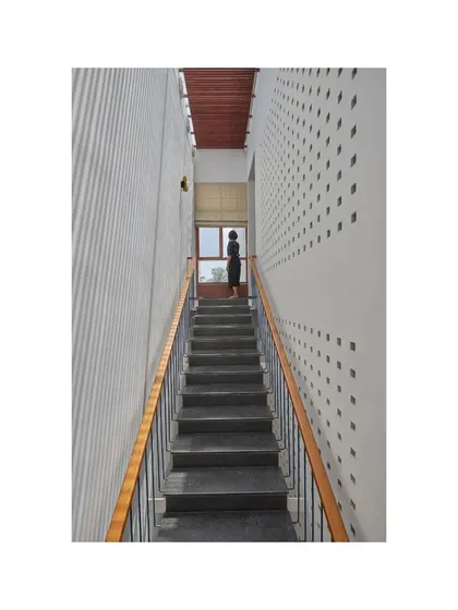 A perspective of the main staircase in the Vikas Residence, highlighting the play of light from the perforated wall.