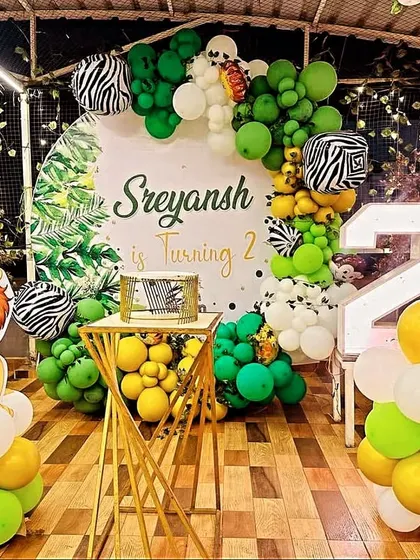 A safari jungle theme for a second birthday, featuring a lion cutout, zebra-print balloons, and a light-up number '2'.