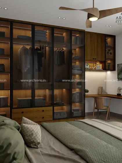 A luxurious walk-in wardrobe with dark wood finishes and smoked glass doors. The integrated LED lighting beautifully showcases the collection inside, turning storage into a style statement.