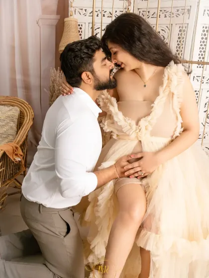 A kneeling pose that beautifully highlights the baby bump and the couple's connection. This shot is part of a light and airy boho-themed maternity session.