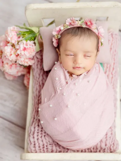 A full view of the sweet pink setup, with the baby nestled in a tiny bed surrounded by pink flowers. It's a perfect theme for a baby girl.